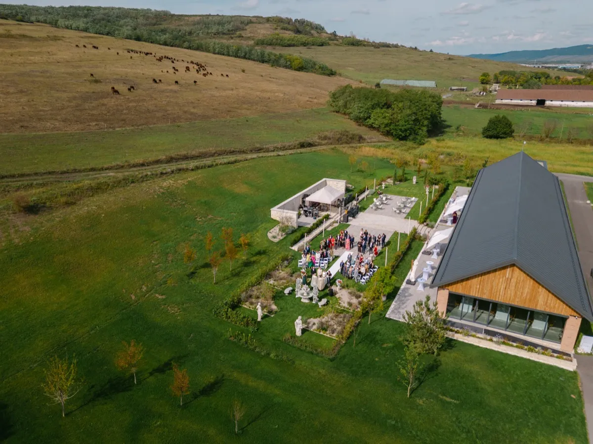 Vedere aeriană de dronă asupra domeniului Wild Hills Jucu, cu dealurile din jur și ceremonia de nuntă în desfășurare